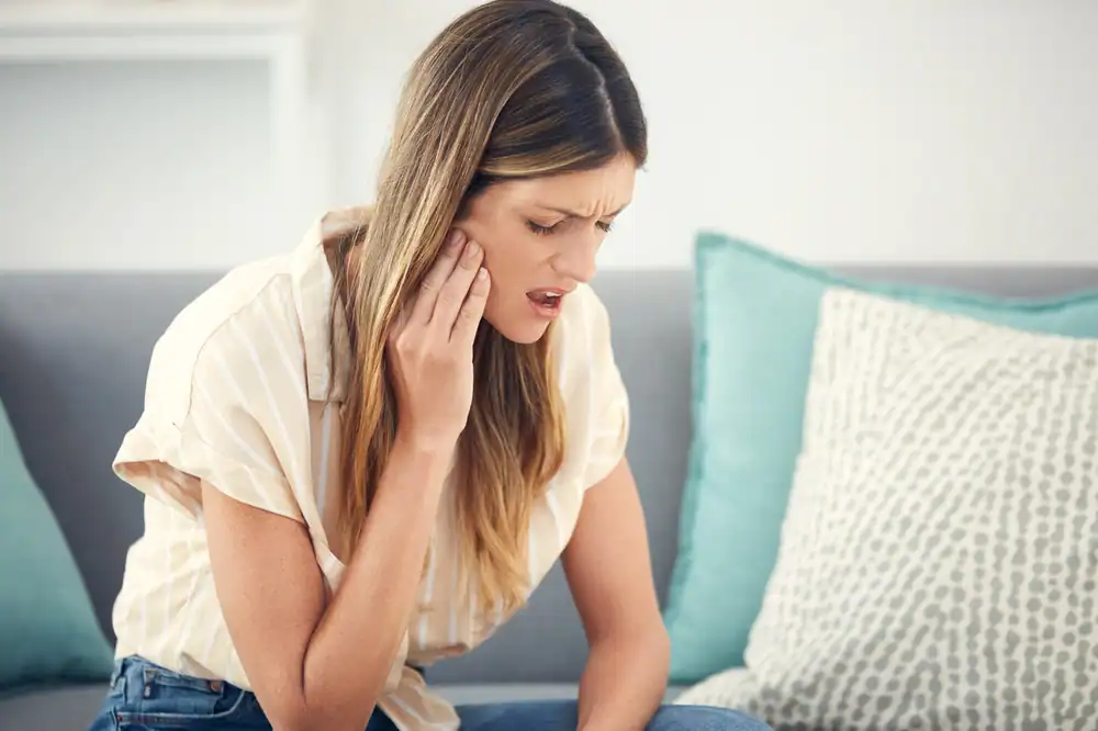 Woman experiencing jaw pain and discomfort, possibly from TMJ or jaw clicking—may benefit from Strategic Hypnotherapy offered by MindShift Mentors.