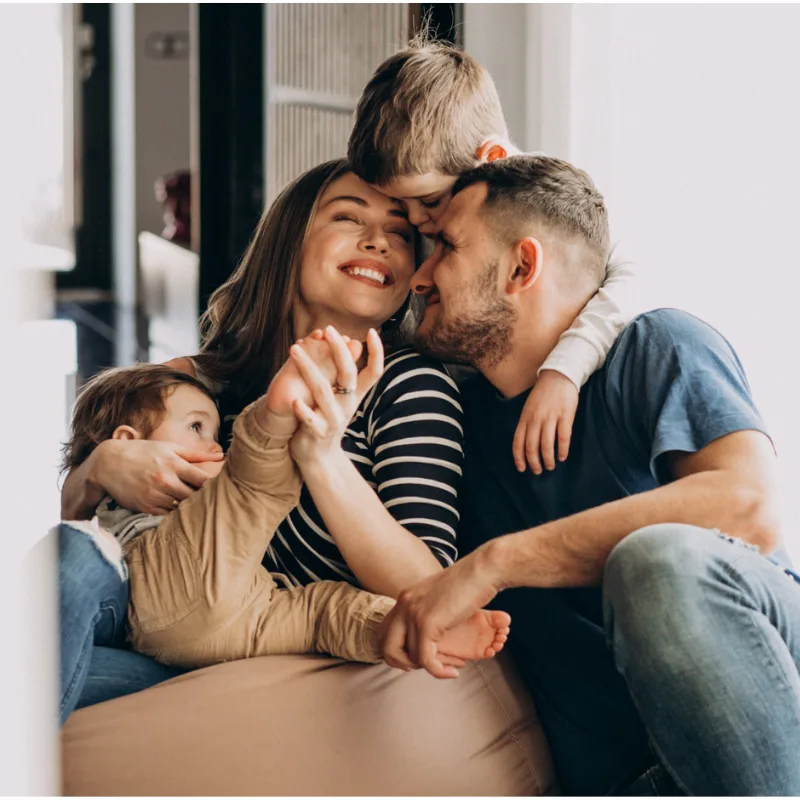 Smiling parents on a sofa cuddling two young children