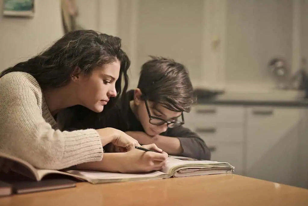 Mother helping her child with homework at the table, showing support and focus as part of an ADHD-friendly homework routine.
