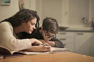 Mother helping her child with homework at the table, showing support and focus as part of an ADHD-friendly homework routine.