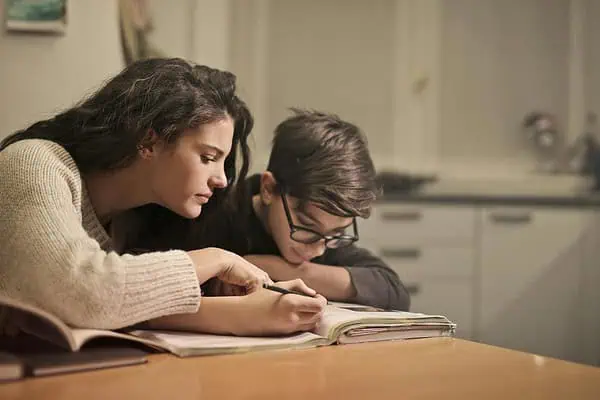 Mother helping her child with homework at the table, showing support and focus as part of an ADHD-friendly homework routine.