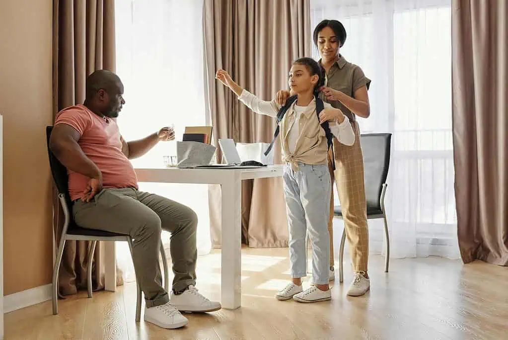 Parents helping their child with a backpack after school at home, showing family support and routine