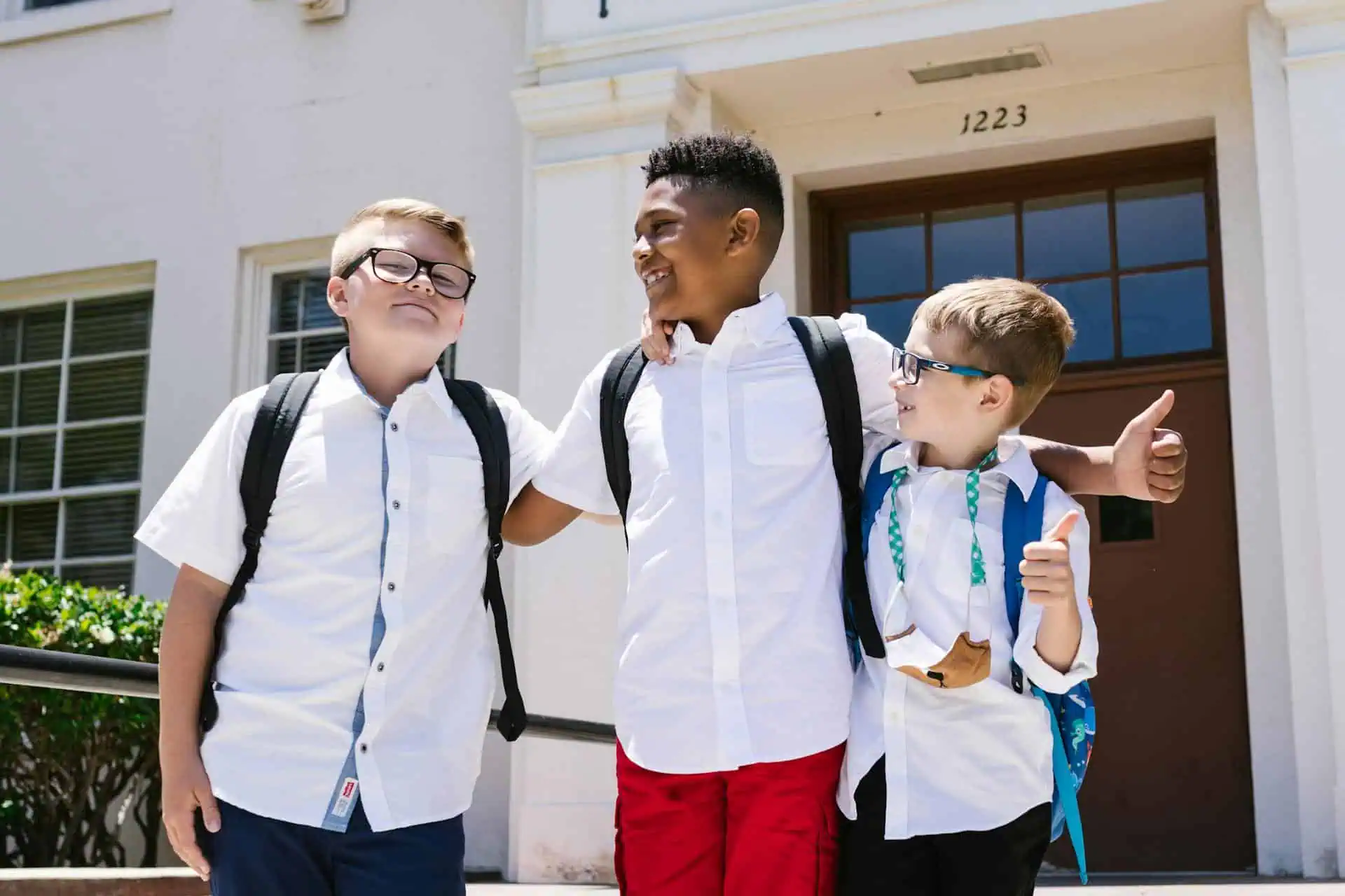 Three school children in uniforms with backpacks smiling and walking together after school. ADHD kids after school meltdown.
