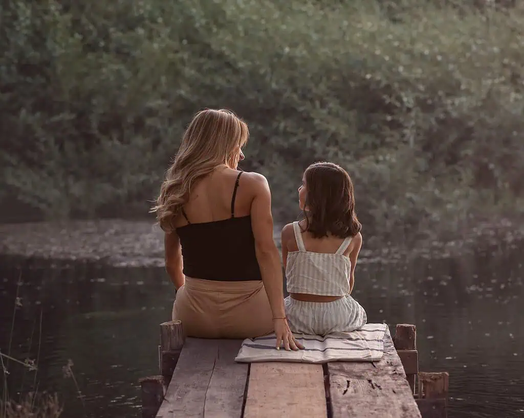 Mother and daughter sitting quietly on a dock by the water, sharing a calm, supportive moment—illustrating mindful parenting for kids with ADHD.