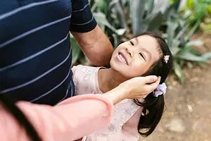 Smiling young girl looking up at a parent, symbolizing the importance of understanding ADHD symptoms in children and providing supportive care.
