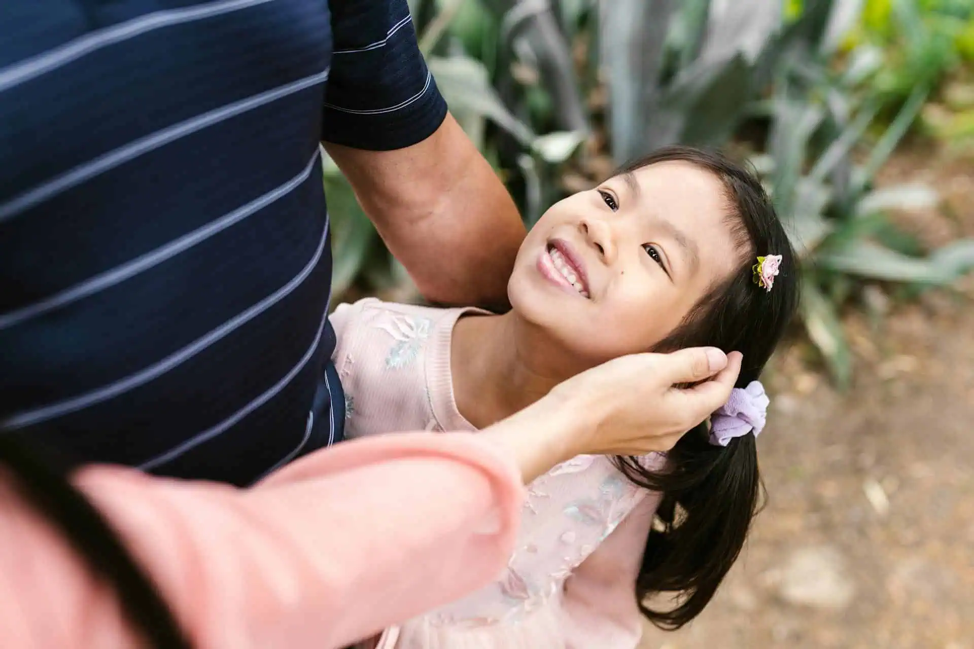 Smiling young girl looking up at a parent, symbolizing the importance of understanding ADHD symptoms in children and providing supportive care.