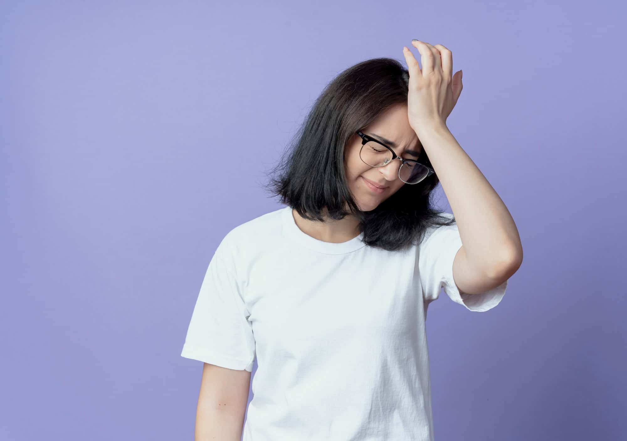 Young woman in glasses looking frustrated, touching her head representing forgetfulness and daily struggles often experienced by women with ADHD.
