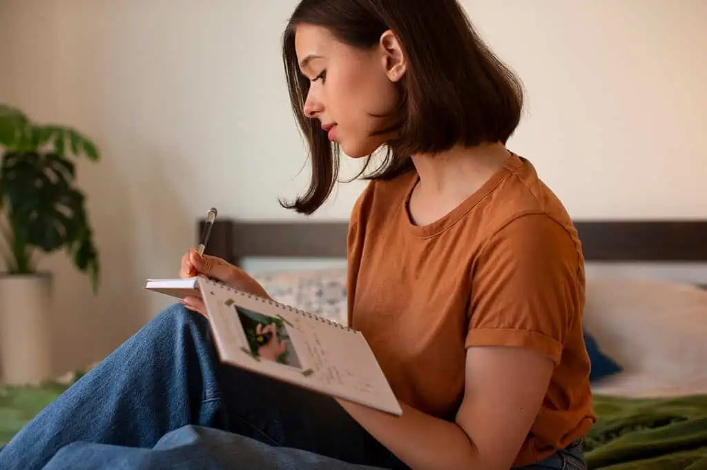 Young woman writing in a notebook at home—using journaling as a coping tool to manage ADHD symptoms and improve daily focus.