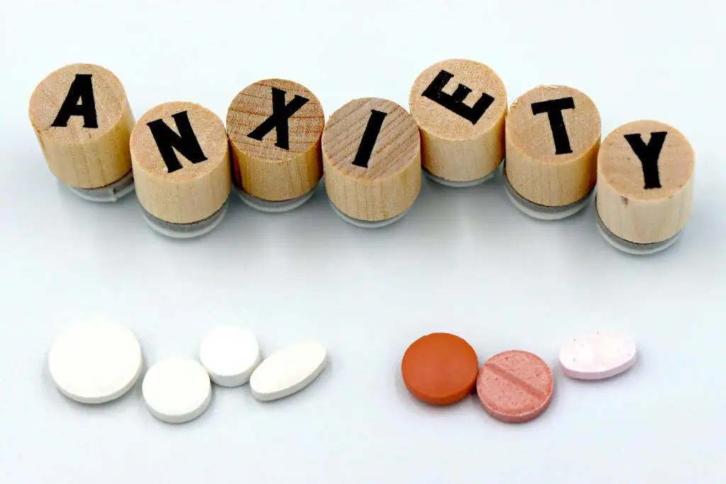 Wooden blocks spelling "ANXIETY" next to various colored pills, symbolizing the use of medication for anxiety and related concerns.