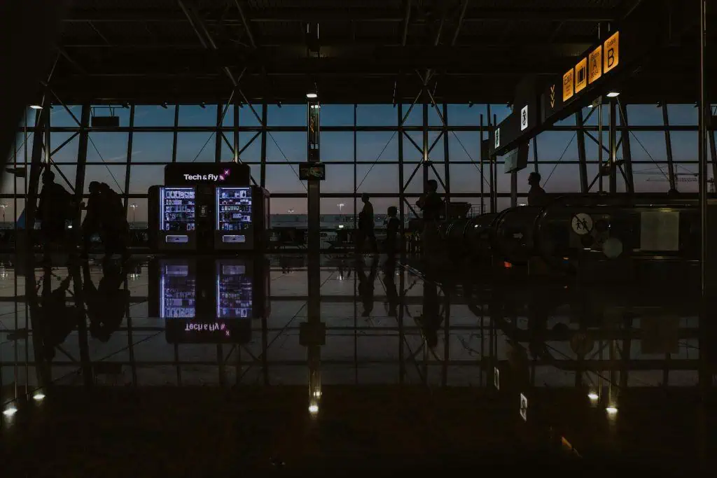 Silhouetted travelers walking through a dimly lit airport terminal at dusk, symbolizing pre-flight anxiety and the tense atmosphere before boarding.