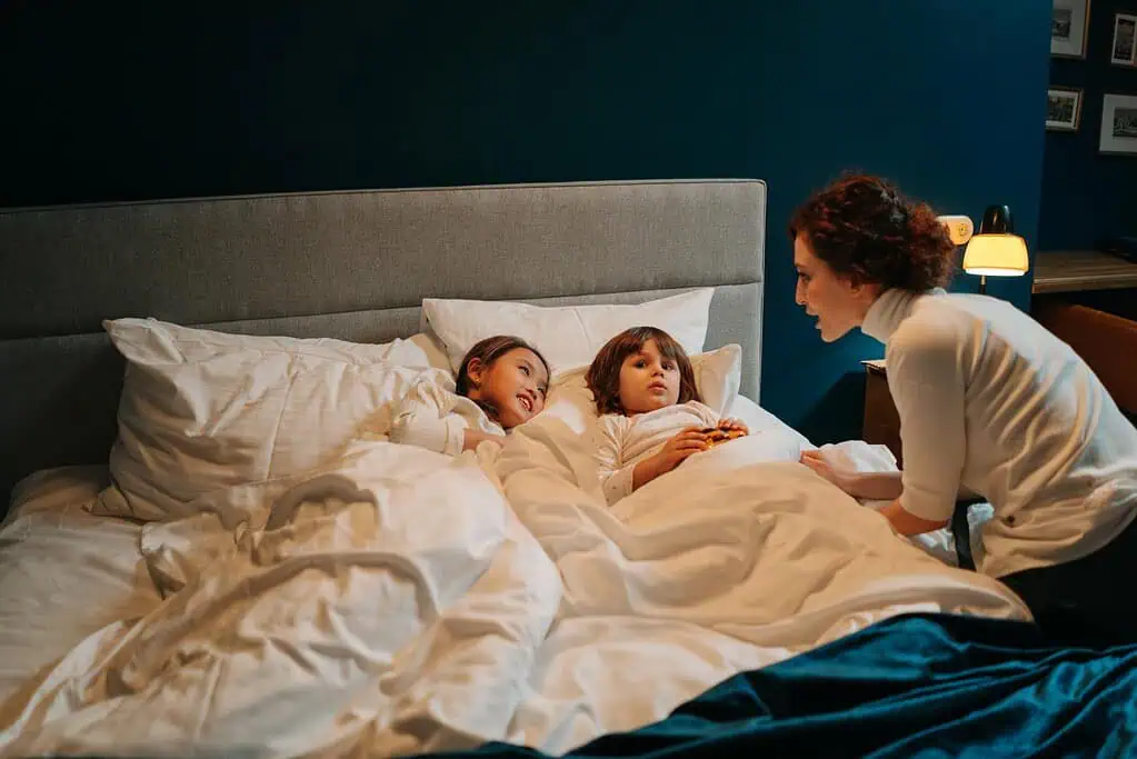 Mother talking to two children in bed during bedtime, creating a supportive and calming bedtime routine