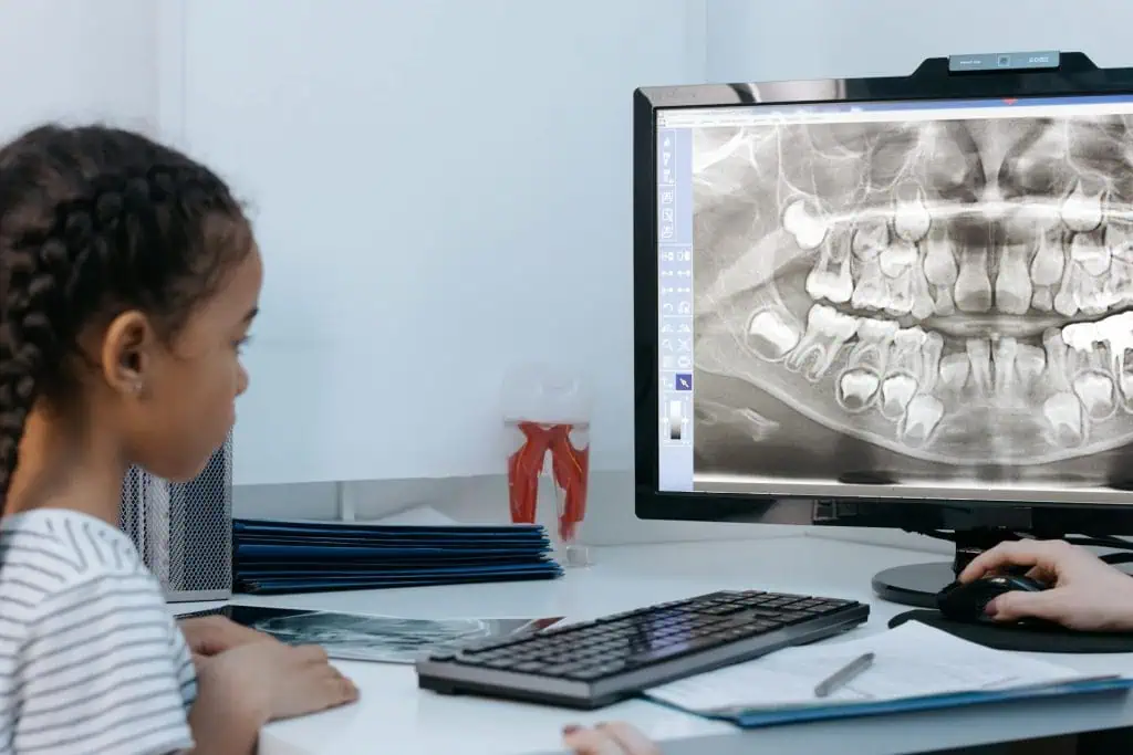 A child viewing a dental X-ray with a dentist during a consultation about bruxism in kids.