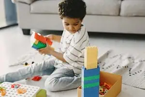 A young boy playing with colorful building blocks, illustrating motor skill development challenges related to Developmental Coordination Disorder (DCD).