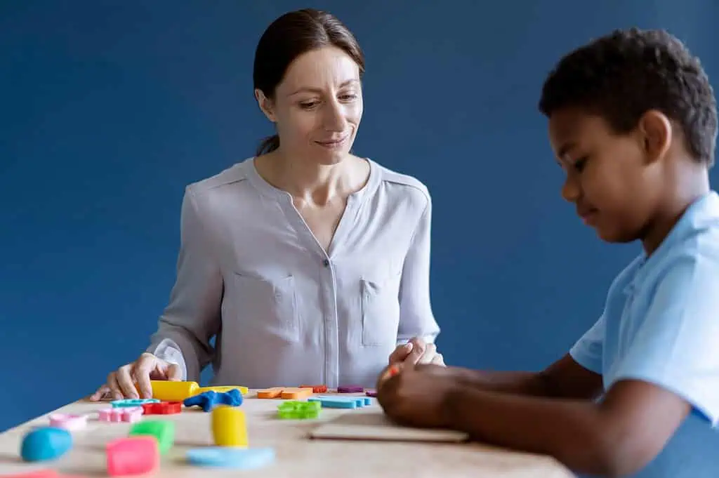 A therapist guiding a young boy through a hands-on activity with colorful tools, supporting motor skills development for children with Developmental Coordination Disorder (DCD).