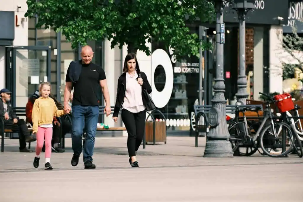 A man and woman walking side by side with their daughter in an urban area, suggesting co-parenting in everyday life.
