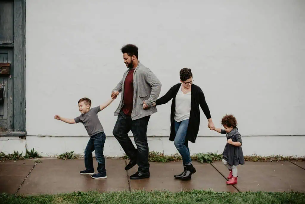 A mother and father walking on opposite ends with their children, holding hands, representing shared parenting after separation.