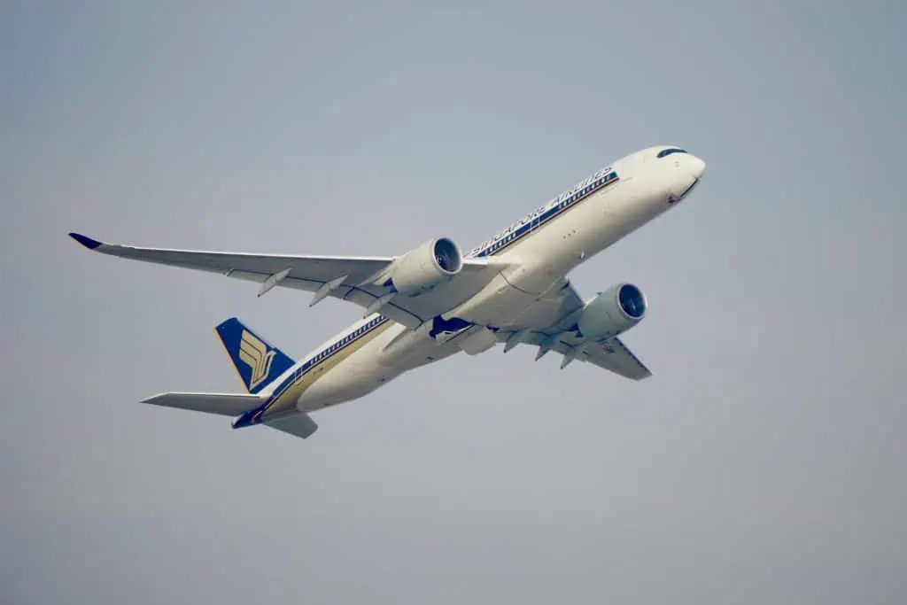 Singapore Airlines airplane in mid-flight against a clear sky, viewed from below, symbolizing the fear of flying and loss of control.