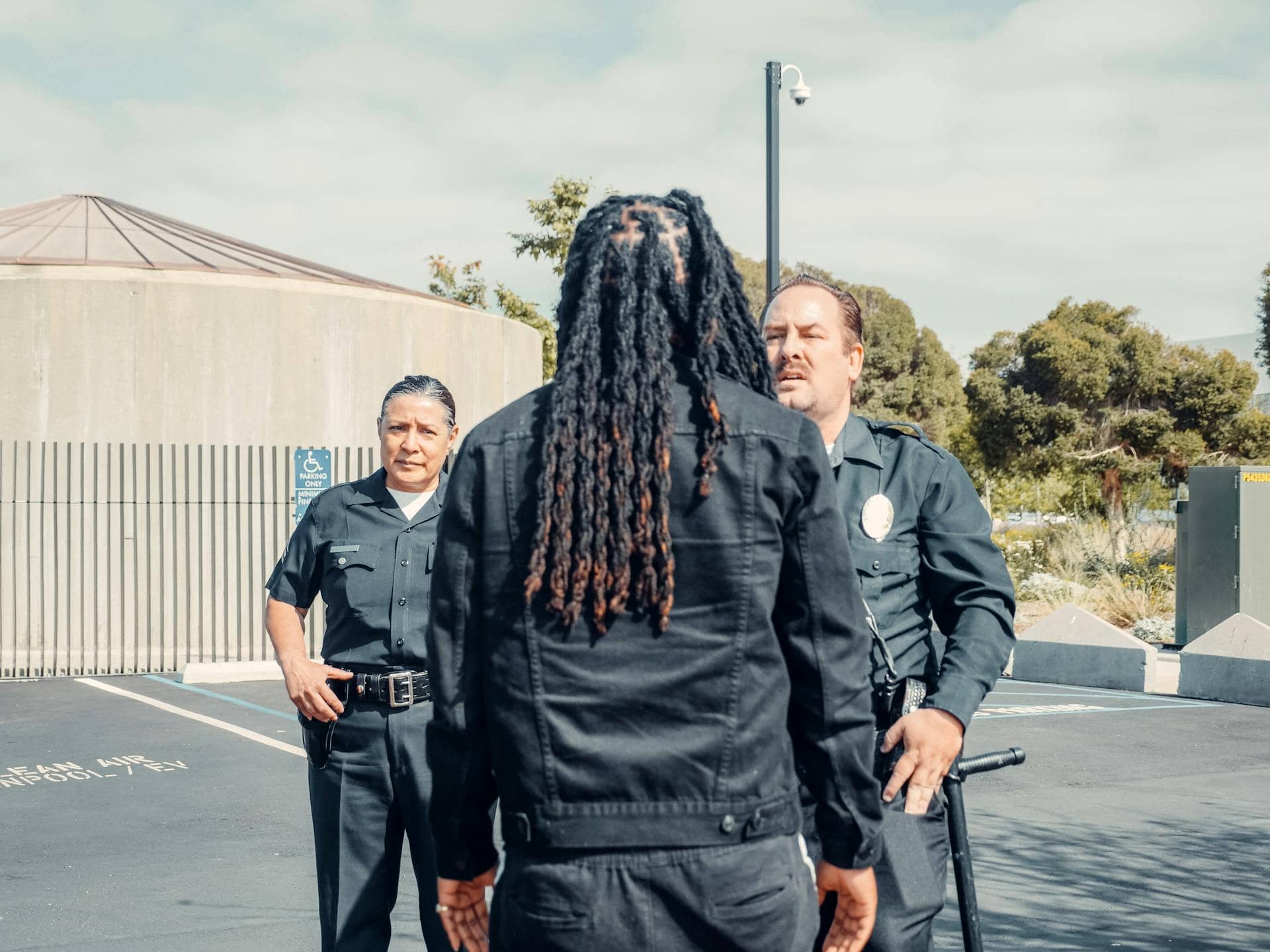 Correctional officers are seen outdoors in a tense confrontation, possibly managing an incident or conflict, with serious expressions and a controlled but alert stance.