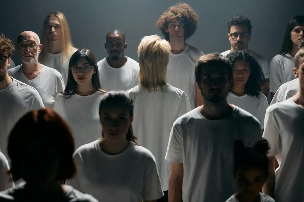 Group of people wearing white shirts with one person turned away, symbolizing disconnection, isolation, and the experience of disassociation