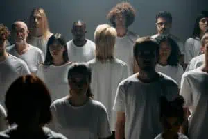Group of people wearing white shirts with one person turned away, symbolizing disconnection, isolation, and the experience of disassociation