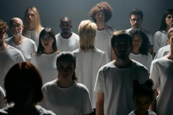 Group of people wearing white shirts with one person turned away, symbolizing disconnection, isolation, and the experience of disassociation