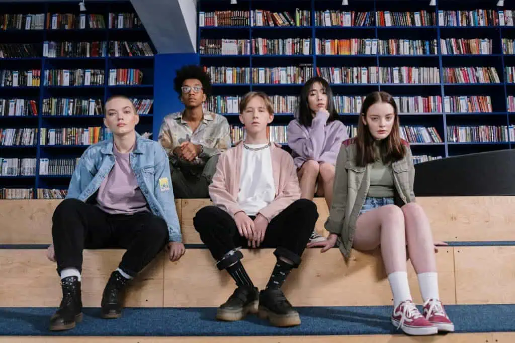 Group of diverse teenagers sitting quietly in a library, appearing thoughtful or serious