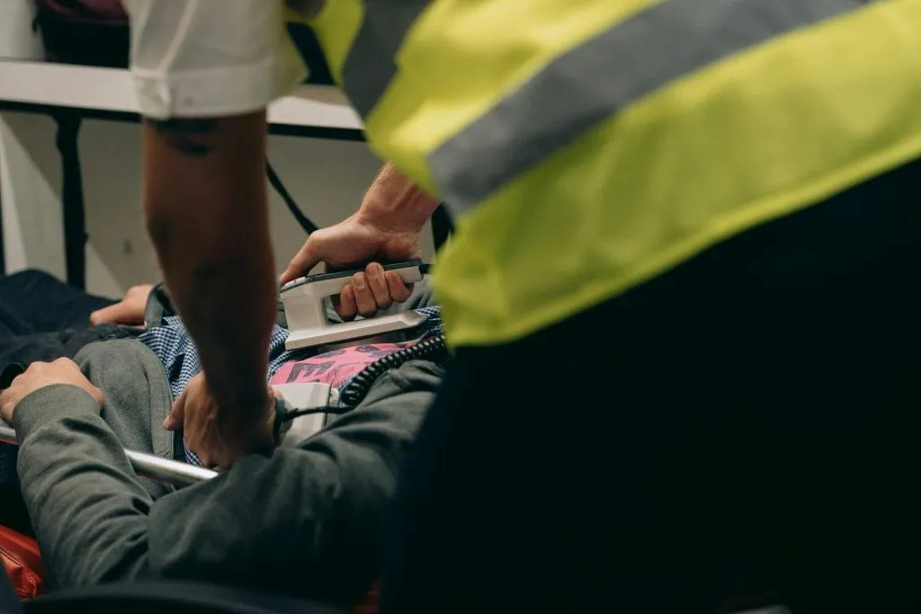 Emergency medical personnel performing defibrillation on a patient lying on a stretcher, simulating a critical rescue scenario.