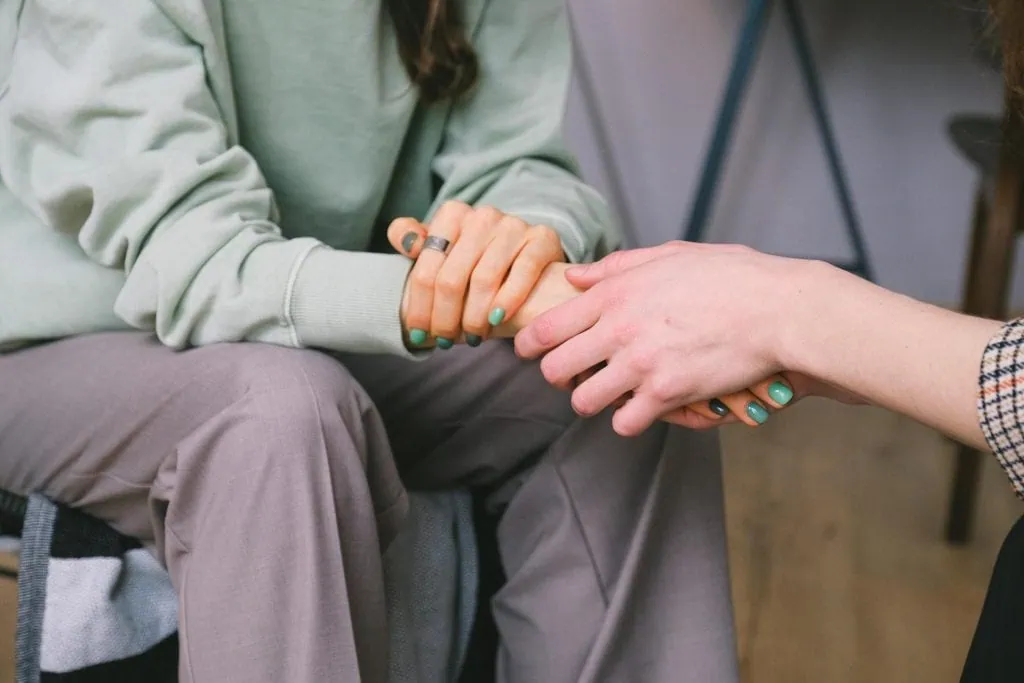 Close-up of two people holding hands in a comforting gesture, symbolizing support and empathy.