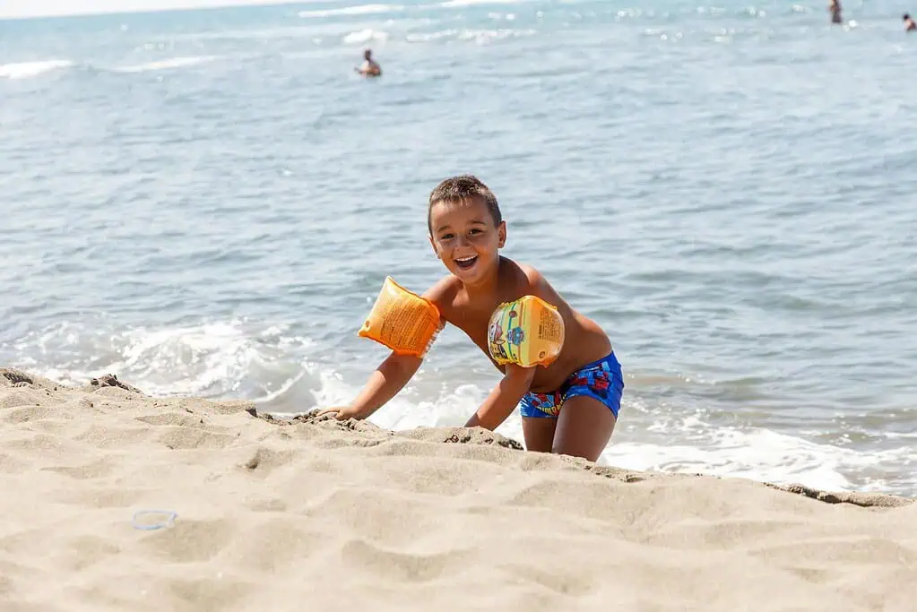 Smiling young boy playing on the beach, representing the difference between natural high energy and ADHD symptoms in children.