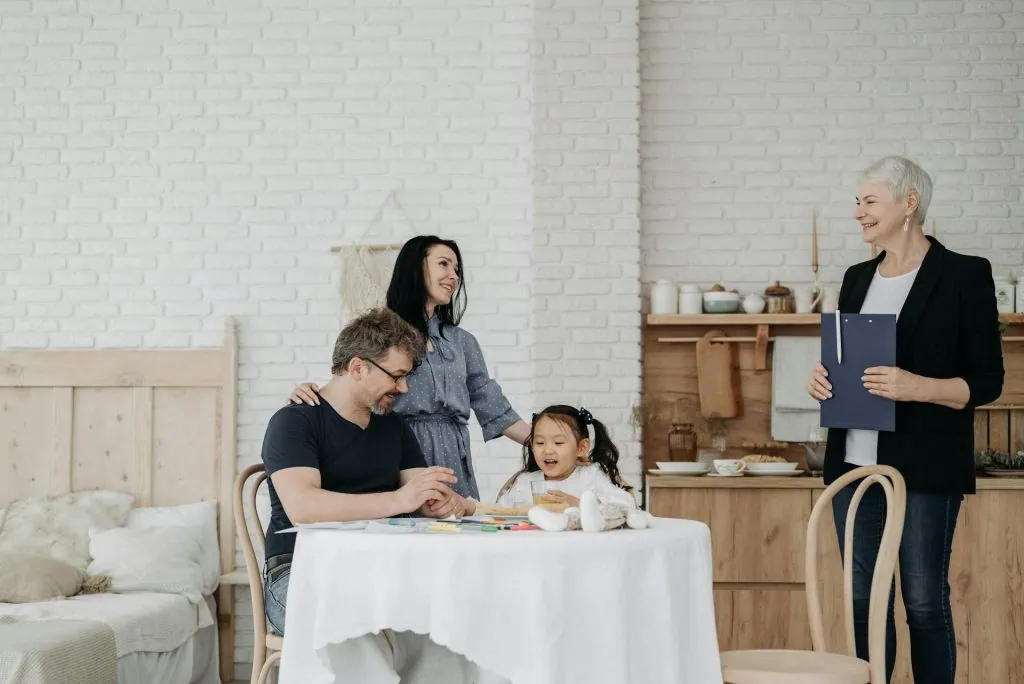 Smiling family interacting with a professional hypnotherapist during a relaxed in-home session focused on emotional healing and connection.