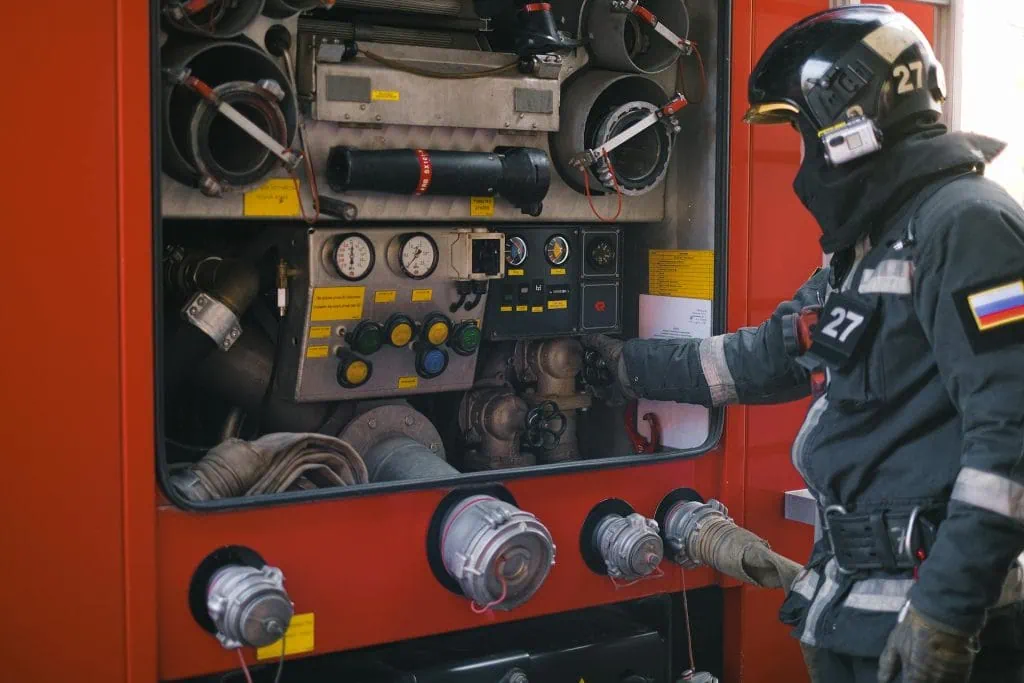 Firefighter in full gear operating the control panel of a fire engine, representing focus and precision in emergency response