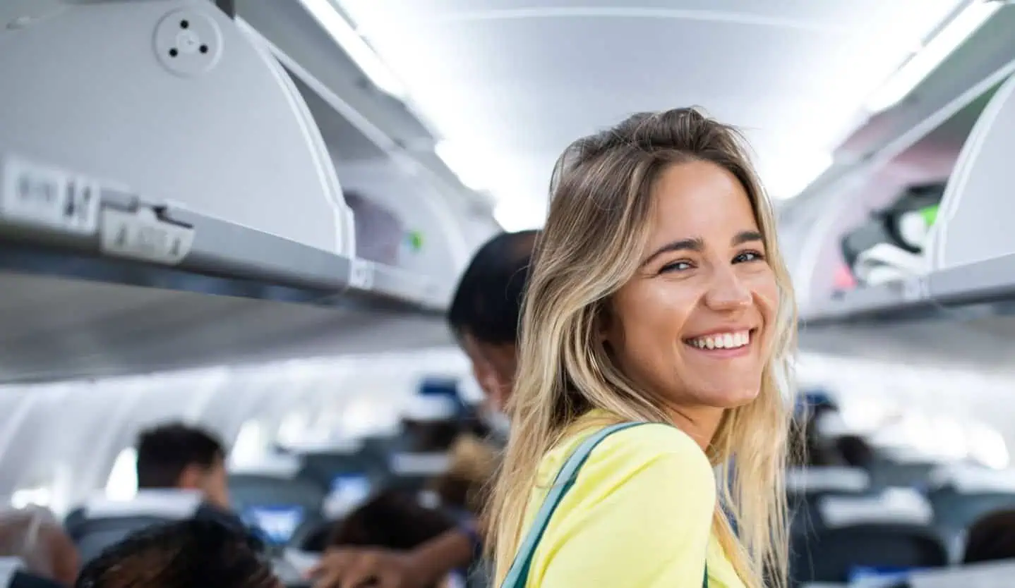 Nervous woman gripping airplane seat armrest during flight, showing signs of fear of flying