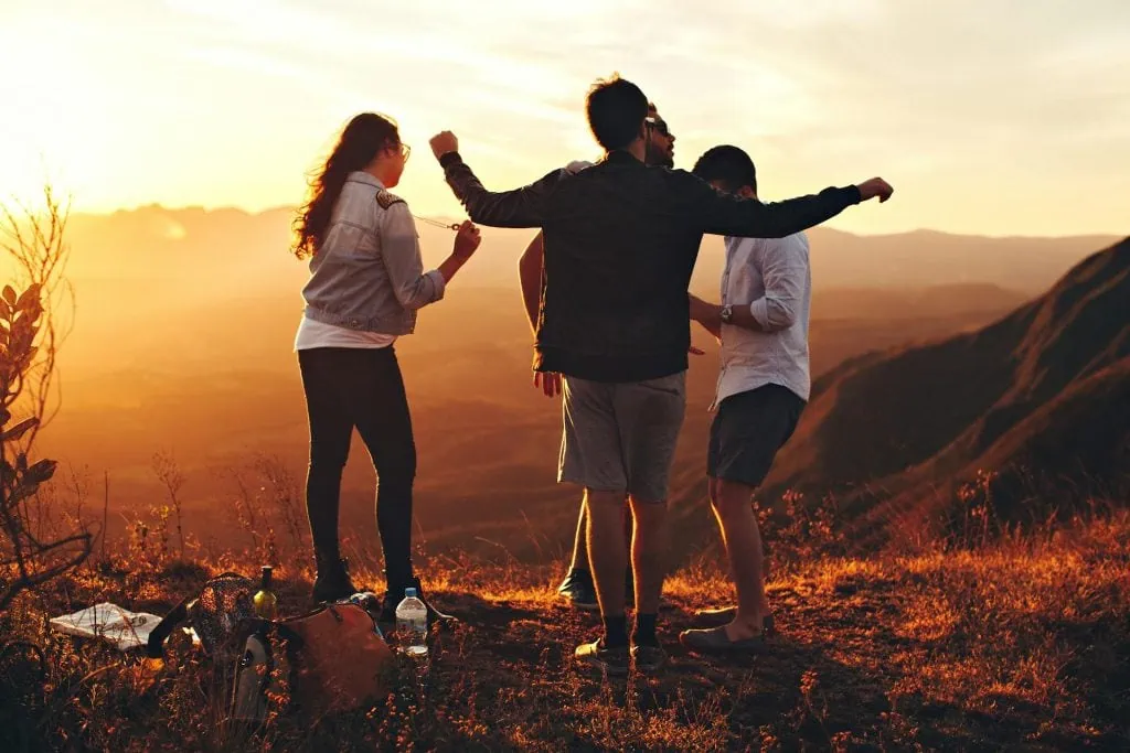 Group of friends unwinding and enjoying a sunset hike on a mountain