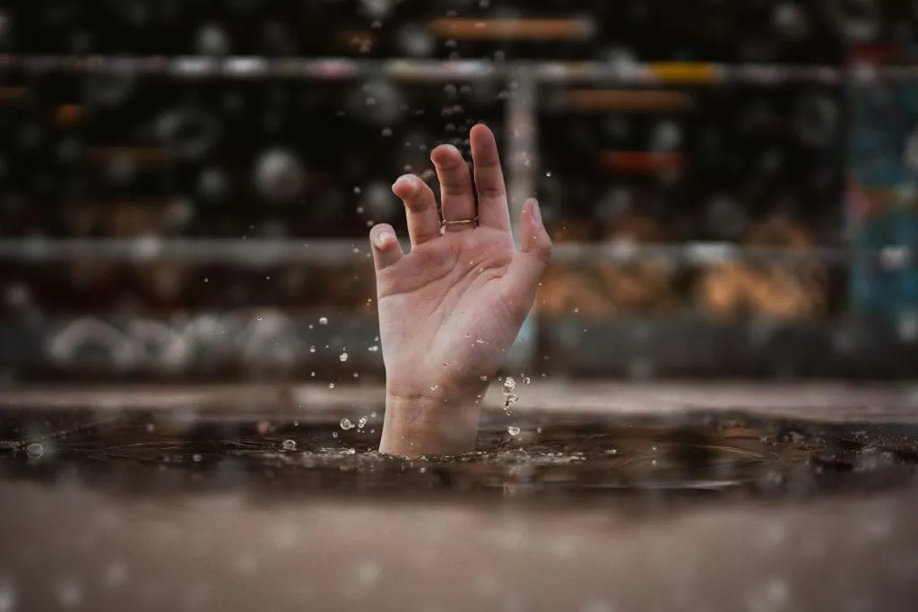 A hand reaching out of water, symbolizing emotional overwhelm, stress, or a cry for help during a mental health crisis.