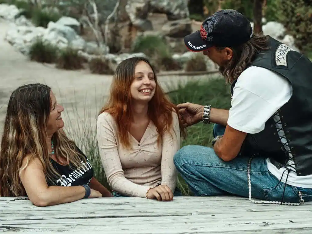 Smiling teenage girl spending time outdoors with supportive parents, showing a positive family connection and emotional well-being