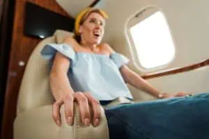 Nervous woman gripping airplane seat armrest during flight, showing signs of fear of flying