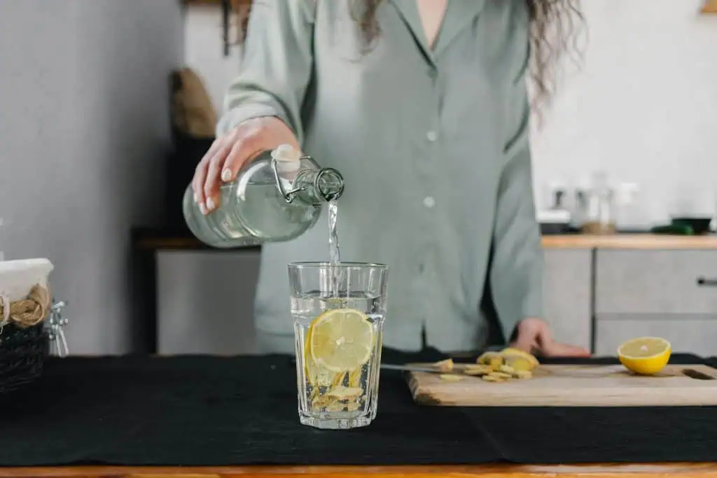 Person pouring lemon water into a glass, emphasizing hydration before a flight to reduce anxiety
