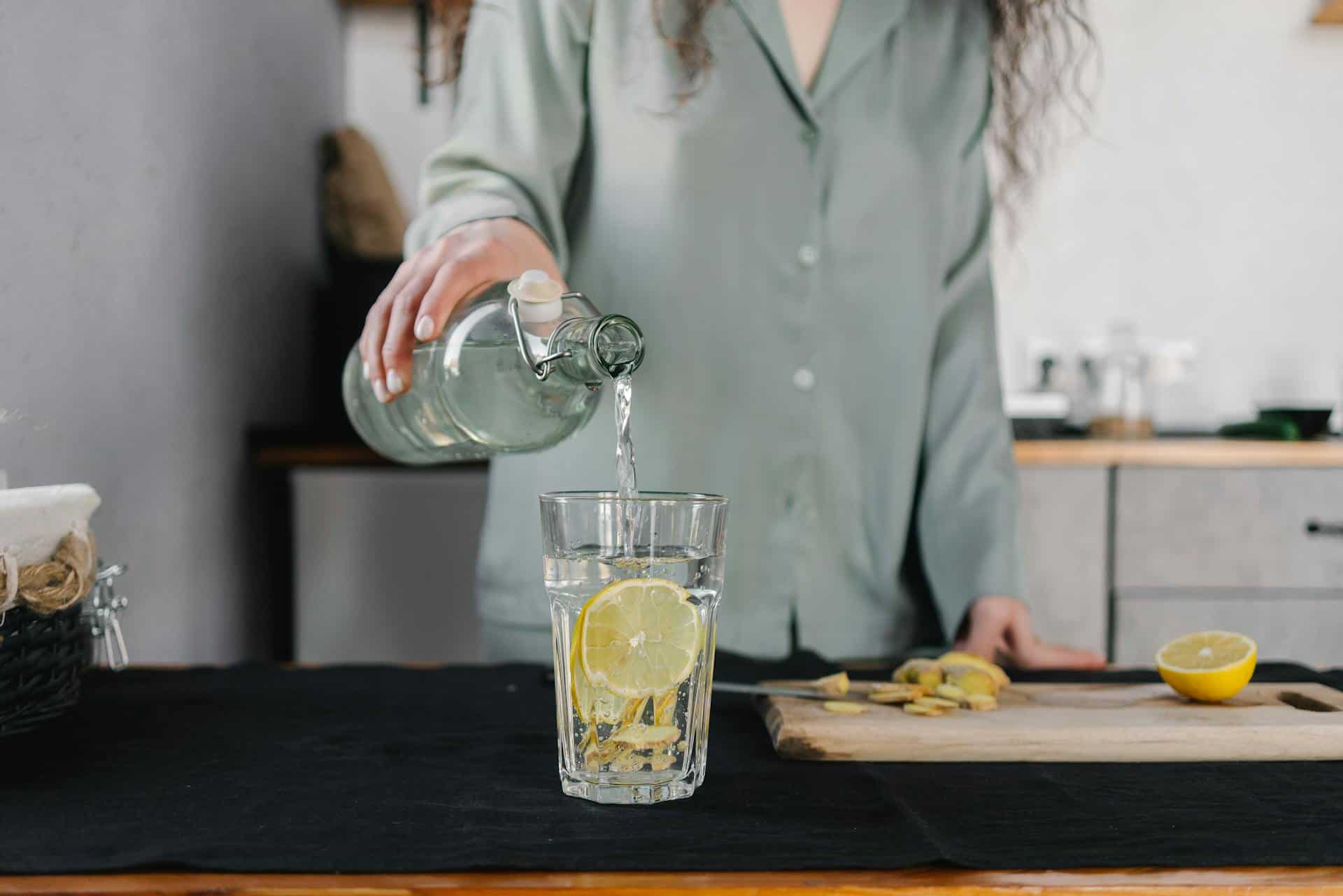 Person pouring lemon water into a glass, emphasizing hydration before a flight to reduce anxiety