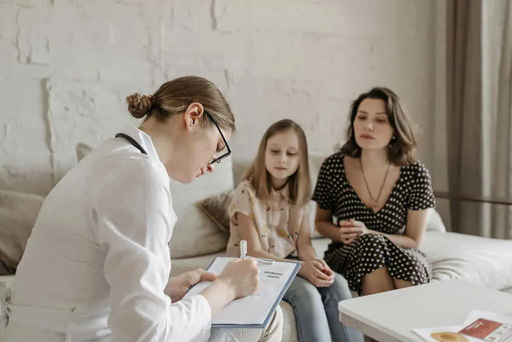 Therapist conducting a hypnotherapy for ADHD kids consultation with a mother and daughter in a calm, supportive setting.