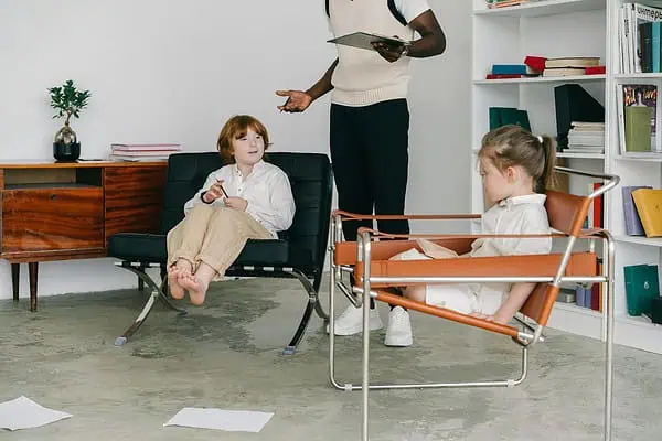 Therapist leading a hypnotherapy for ADHD kids session with two children in a modern, comfortable office setting.