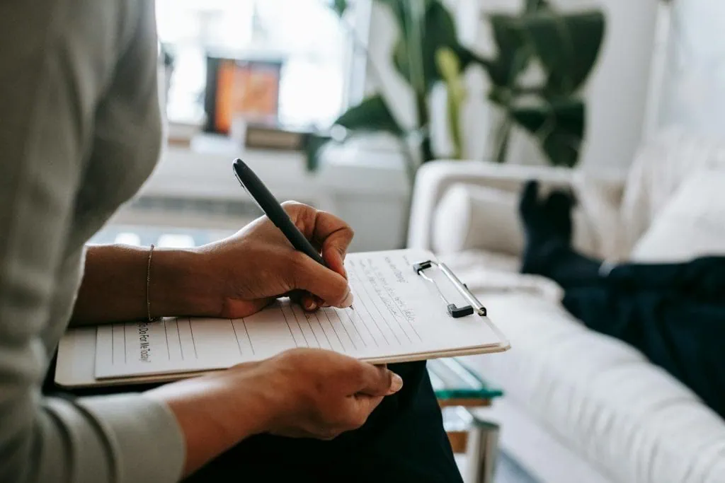 Therapist taking notes during a hypnotherapy session.