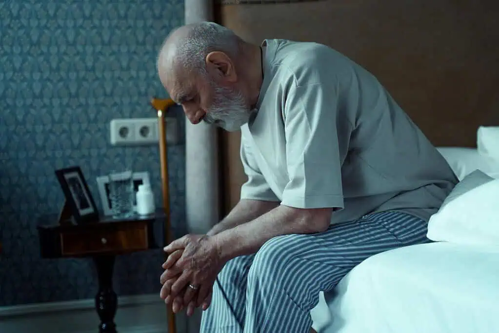 Elderly man sitting on bed feeling tired, representing challenges of living with Dyspraxia in later life