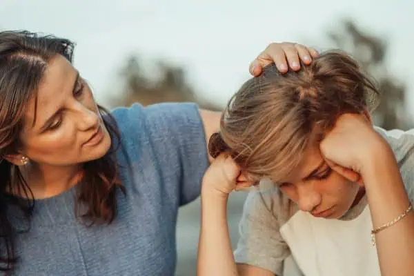 Concerned mother comforting her stressed teenage son during an emotional moment