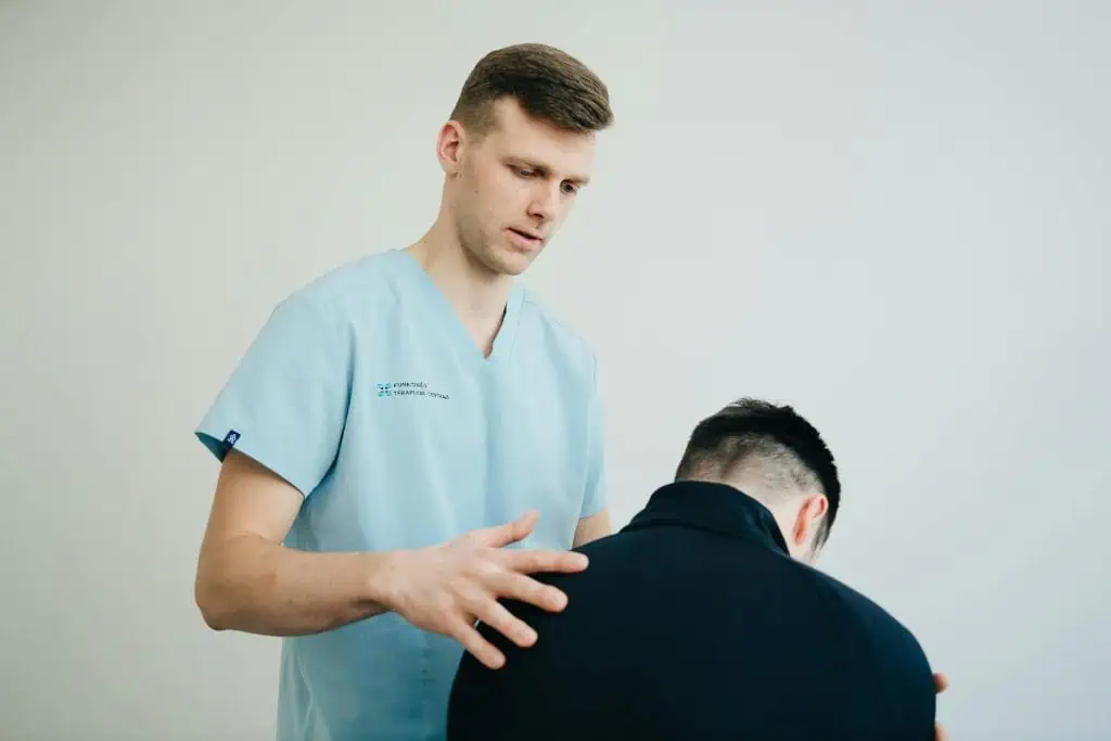Male physical therapist assessing a man's posture and neck alignment during a therapy session
