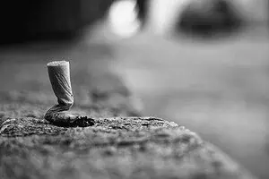 Close-up of a crushed cigarette butt on pavement symbolizing to quit smoking