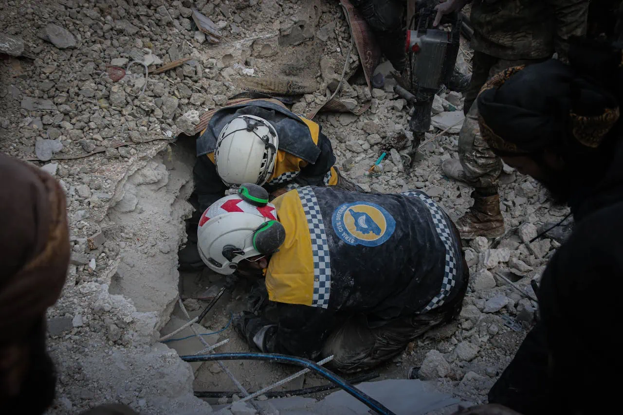 Rescue workers from the White Helmets searching for survivors in rubble after a disaster, focused on saving lives