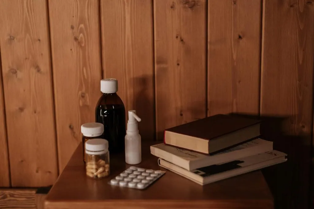 Medicines and books on a wooden nightstand, representing sleep aid safety.