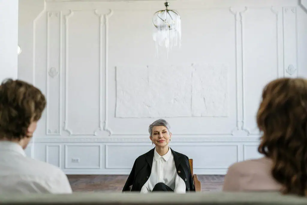 A therapist sits calmly across from a man and woman, suggesting a counseling or mediation session for a separated couple
