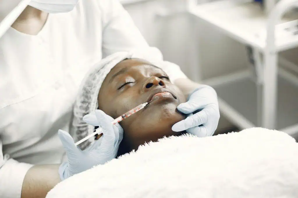 A woman receiving a Botox injection in the jaw area, a common temporary treatment for TMJ Disorder symptoms