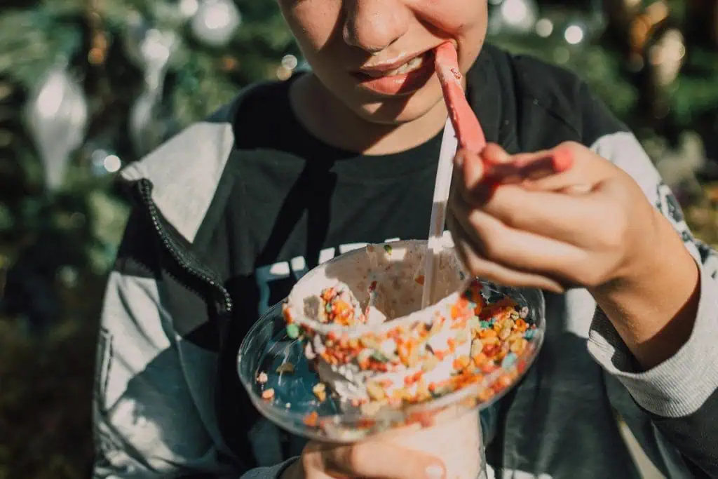 A person eating a colorful dessert with chewy candy, representing foods that may aggravate TMJ disorder symptoms.